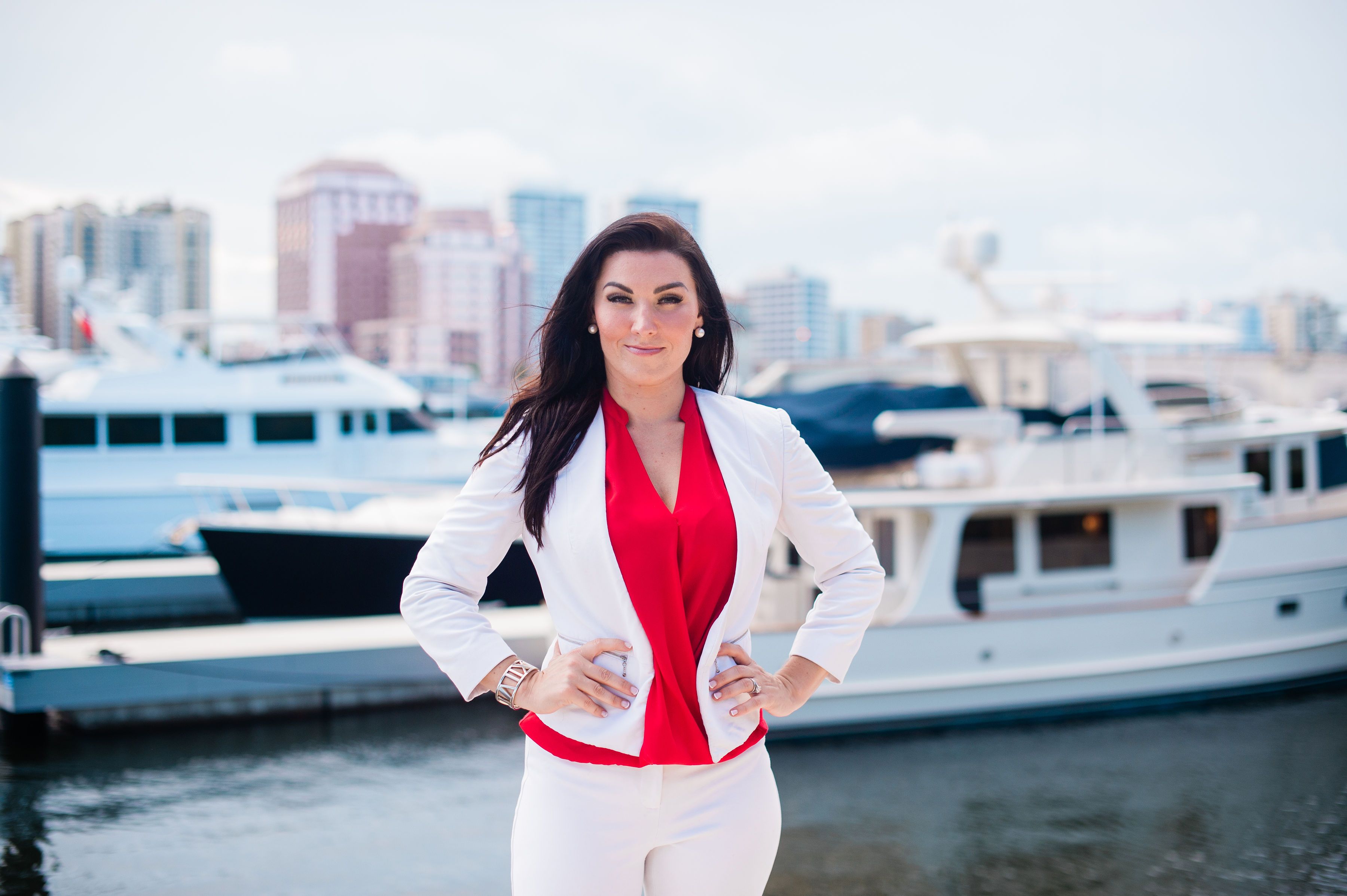 Bridget Hom standing confidently in a red blouse and white blazer beside the waterfront, representing the momentum to take imperfect business action