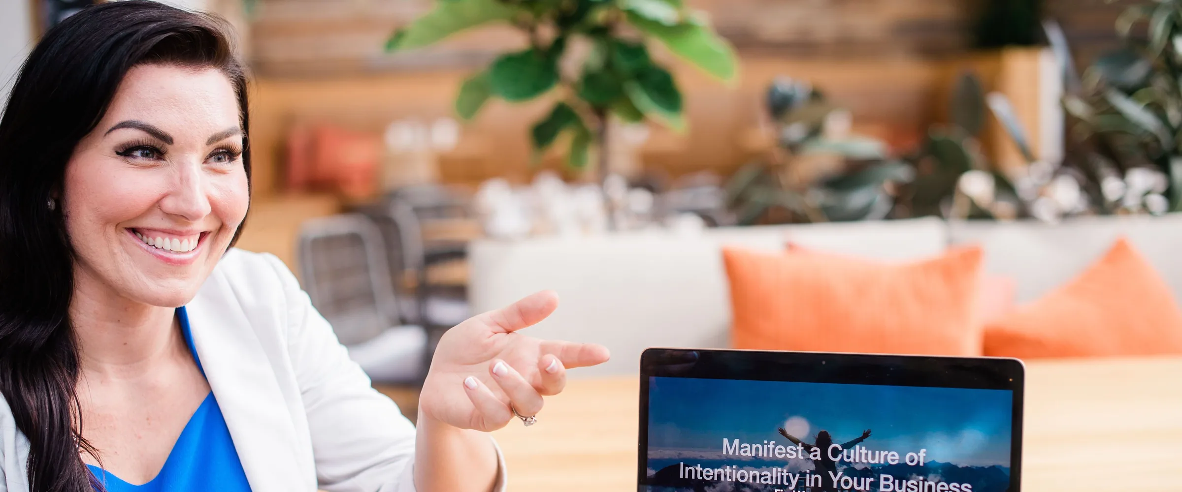 Bridget Hom smiling across a table with a client and laptop during a business coaching conversation